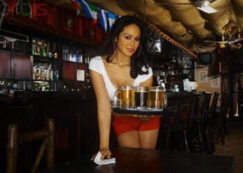 Sexy young waitress serving beer in bar --- Image by © Hola Images/Corbis