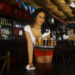 Sexy young waitress serving beer in bar --- Image by © Hola Images/Corbis