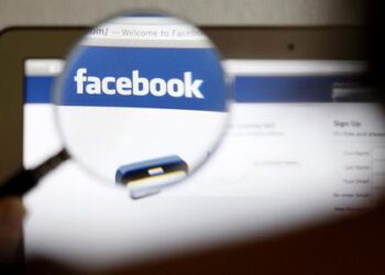 A Facebook logo on a computer screen is seen through a magnifying glass in Bern in this file photo illustration taken May 19, 2012. Facebook Inc said it will start charging businesses to run Offers on its social network, turning a previously free service into a potential revenue generator at a time when Wall Street is demanding new sources of growth and profit from the company.  REUTERS/Thomas Hodel/File  (SWITZERLAND - Tags: BUSINESS)