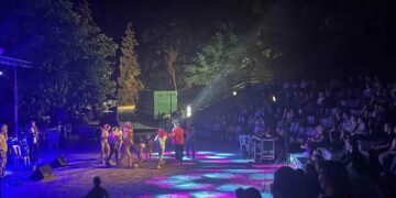 Μια δυναμική σκηνή χορευτών στο Υπαίθριο Θέατρο Σερβίων κατά τη διάρκεια του Φεστιβάλ Σερβίων, με το κοινό να παρακολουθεί με ενθουσιασμό.