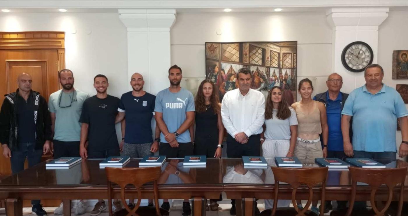 Μέλη της εθνικής κωπηλασίας στέκονται όρθια σε ένα δωμάτιο στην Καστοριά, έτοιμοι για το Παγκόσμιο Πρωτάθλημα.