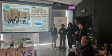 A group of people stand in a room during the Erasmus Days 2025 event, with a projected image of a historical scene and the Erasmus+ logo visible on a screen.