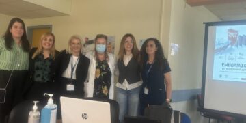 Μια ομάδα επαγγελματιών υγείας στέκεται χαμογελαστοί μπροστά από έναν φορητό υπολογιστή σε μια ημερίδα για τον αντιγριπικό εμβολιασμό στο Γενικό Νοσοκομείο Κοζάνης.