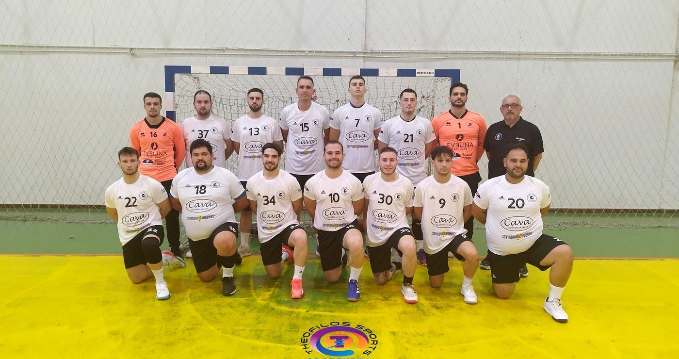 The handball team Αμύντας Αμυνταίου poses for a group photo on the court after a match, wearing dark and light uniforms.