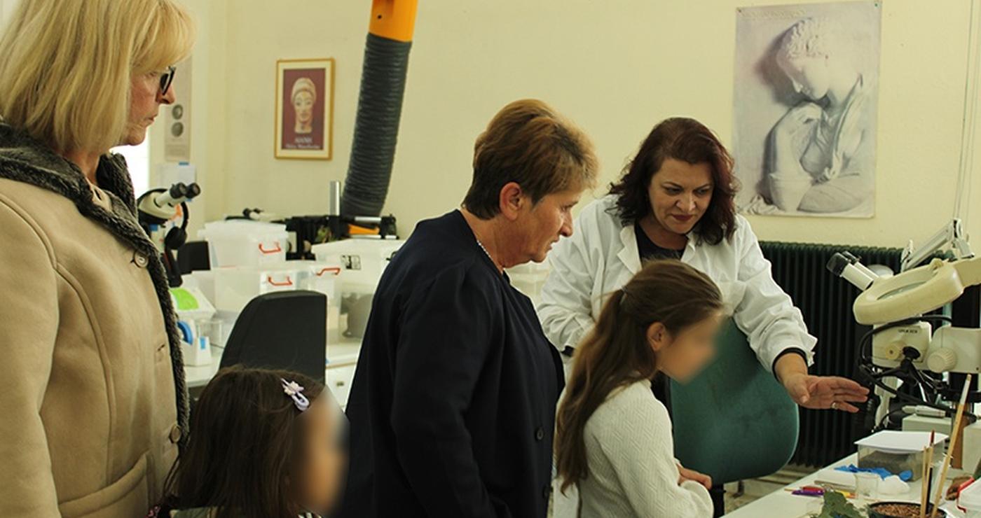 Μια συντηρήτρια αρχαιοτήτων εξηγεί τη διαδικασία συντήρησης σε μια ομάδα επισκεπτών, συμπεριλαμβανομένων παιδιών, στο εργαστήριο του Αρχαιολογικού Μουσείου Αιανής, στο πλαίσιο της δράσης Συντήρηση Αρχαιοτήτων Κοζάνη.