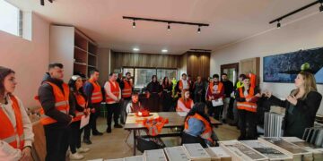 Μια ομάδα υποψηφίων μαθητών, ντυμένοι με γιλέκα, παρακολουθούν μια παρουσίαση στην εκδήλωση έναρξης της Σχολής Μαθητείας για τους Τεχνίτες Βιομηχανικών Αυτοματισμών στα Γρεβενά.