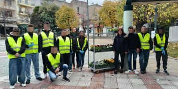 Μια ομάδα μαθητών με γιλέκα υψηλής ορατότητας στέκεται στην κεντρική πλατεία της Φλώρινας, έτοιμοι να ξεκινήσουν τις ανθοφυτεύσεις.