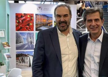 Δύο άνδρες χαμογελούν στο περίπτερο του Δήμου Φλώρινας στην Philoxenia 2025, προβάλλοντας την Φλώρινα ως προορισμό.