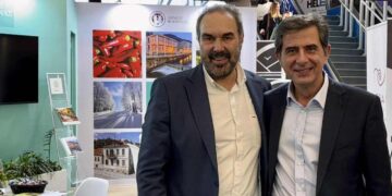 Δύο άνδρες χαμογελούν στο περίπτερο του Δήμου Φλώρινας στην Philoxenia 2025, προβάλλοντας την Φλώρινα ως προορισμό.