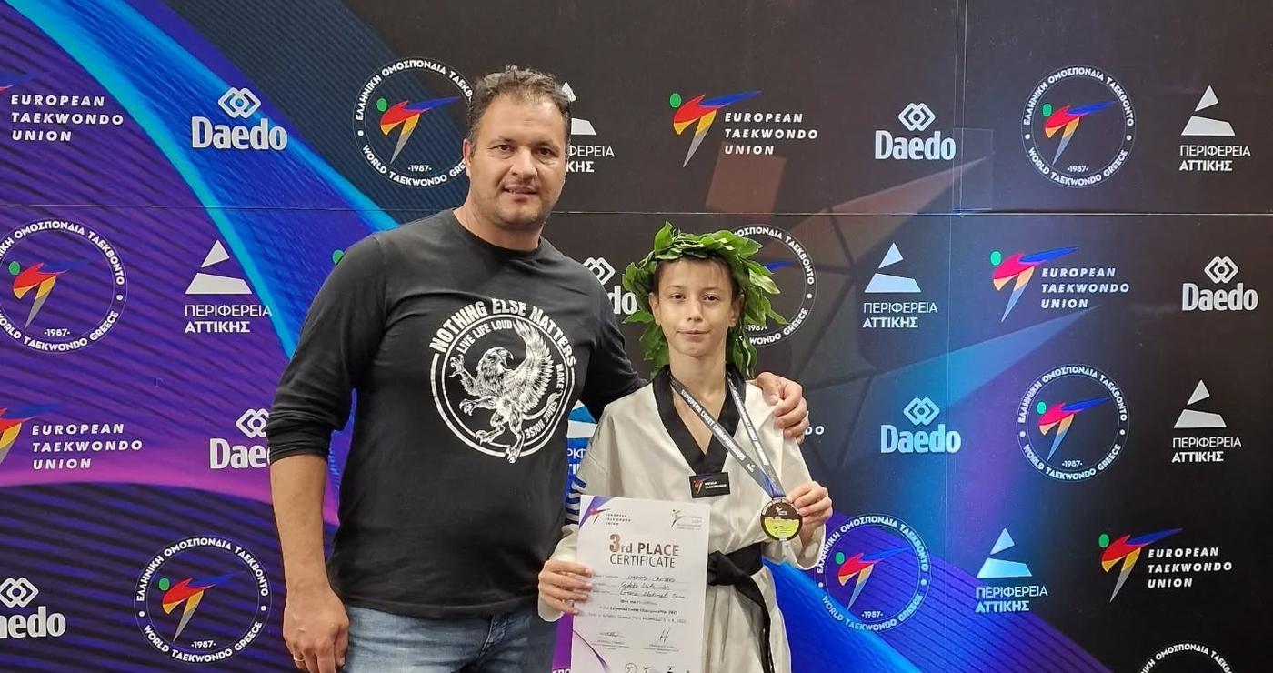 Ο Χρήστος Μάνιος, αθλητής του Taekwondo, στέκεται περήφανα με τον προπονητή του και το χάλκινο μετάλλιό του στο Πανευρωπαϊκό Πρωτάθλημα Taekwondo στην Αθήνα.