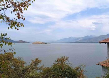 Μια πανοραμική θέα των Πρεσπών με λίμνη, βουνά και ένα μικρό νησί, υπογραμμίζοντας το φυσικό τοπίο των Πρεσπών: Μνημόνιο συνεργασίας.