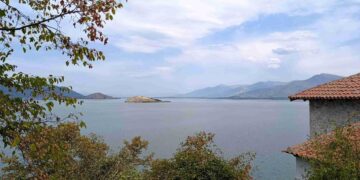 Μια πανοραμική θέα των Πρεσπών με λίμνη, βουνά και ένα μικρό νησί, υπογραμμίζοντας το φυσικό τοπίο των Πρεσπών: Μνημόνιο συνεργασίας.