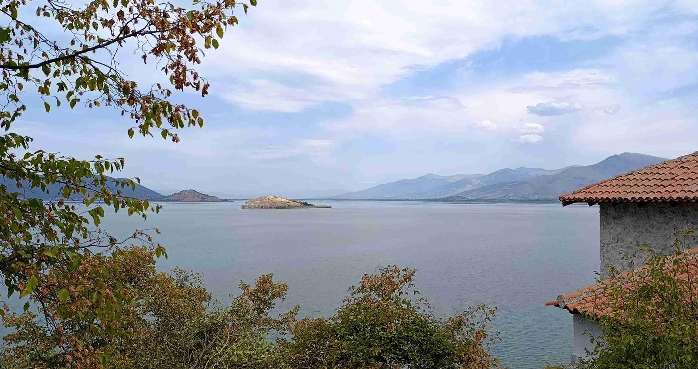 Μια πανοραμική θέα των Πρεσπών με λίμνη, βουνά και ένα μικρό νησί, υπογραμμίζοντας το φυσικό τοπίο των Πρεσπών: Μνημόνιο συνεργασίας.