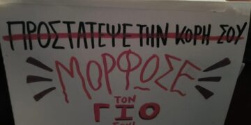 Ένα χειρόγραφο πανό με κόκκινα γράμματα αναγράφει "Προστατεύστε την κόρη σου - Μορφωστε τον γιο σου!" στο θεατρικό εργαστήρι για τη βία κατά των γυναικών.