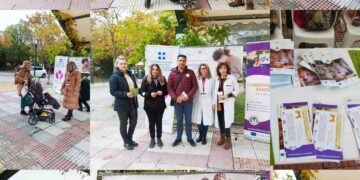 Μια ομάδα ανθρώπων στέκεται χαμογελαστοί μπροστά από ένα λευκό πανό με το λογότυπο του Συμβουλευτικού Κέντρου Δήμου Φλώρινας κατά τη διάρκεια της δράσης ενημέρωσης για τον μητρικό θηλασμό.