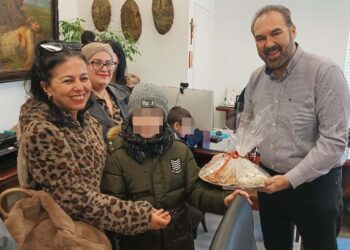 Μια χαμογελαστή γυναίκα και ένας μαθητής του Ειδικού Δημοτικού Σχολείου Φλώρινας προσφέρουν χριστουγεννιάτικα γλυκά στον Δήμαρχο Φλώρινας, κ. Βασίλη Γιαννάκη, κατά την επίσκεψή τους στο Δημαρχείο του δήμος φλώρινας.