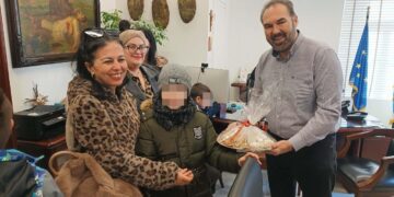 Μια χαμογελαστή γυναίκα και ένας μαθητής του Ειδικού Δημοτικού Σχολείου Φλώρινας προσφέρουν χριστουγεννιάτικα γλυκά στον Δήμαρχο Φλώρινας, κ. Βασίλη Γιαννάκη, κατά την επίσκεψή τους στο Δημαρχείο του δήμος φλώρινας.