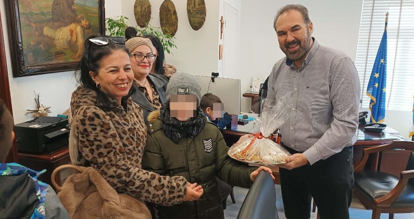 Μια χαμογελαστή γυναίκα και ένας μαθητής του Ειδικού Δημοτικού Σχολείου Φλώρινας προσφέρουν χριστουγεννιάτικα γλυκά στον Δήμαρχο Φλώρινας, κ. Βασίλη Γιαννάκη, κατά την επίσκεψή τους στο Δημαρχείο του δήμος φλώρινας.