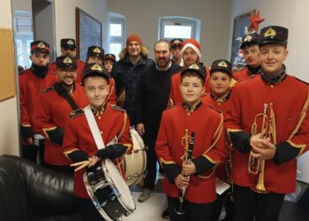 Μια ομάδα μαθητών της φιλαρμονικής του Δήμου Φλώρινας, ντυμένοι με κόκκινα στολή, εψάλλουν χριστουγεννιατικα καλαντα στο Δημαρχείο Φλώρινας.