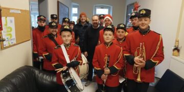 Μια ομάδα μαθητών της φιλαρμονικής του Δήμου Φλώρινας, ντυμένοι με κόκκινα στολή, εψάλλουν χριστουγεννιατικα καλαντα στο Δημαρχείο Φλώρινας.