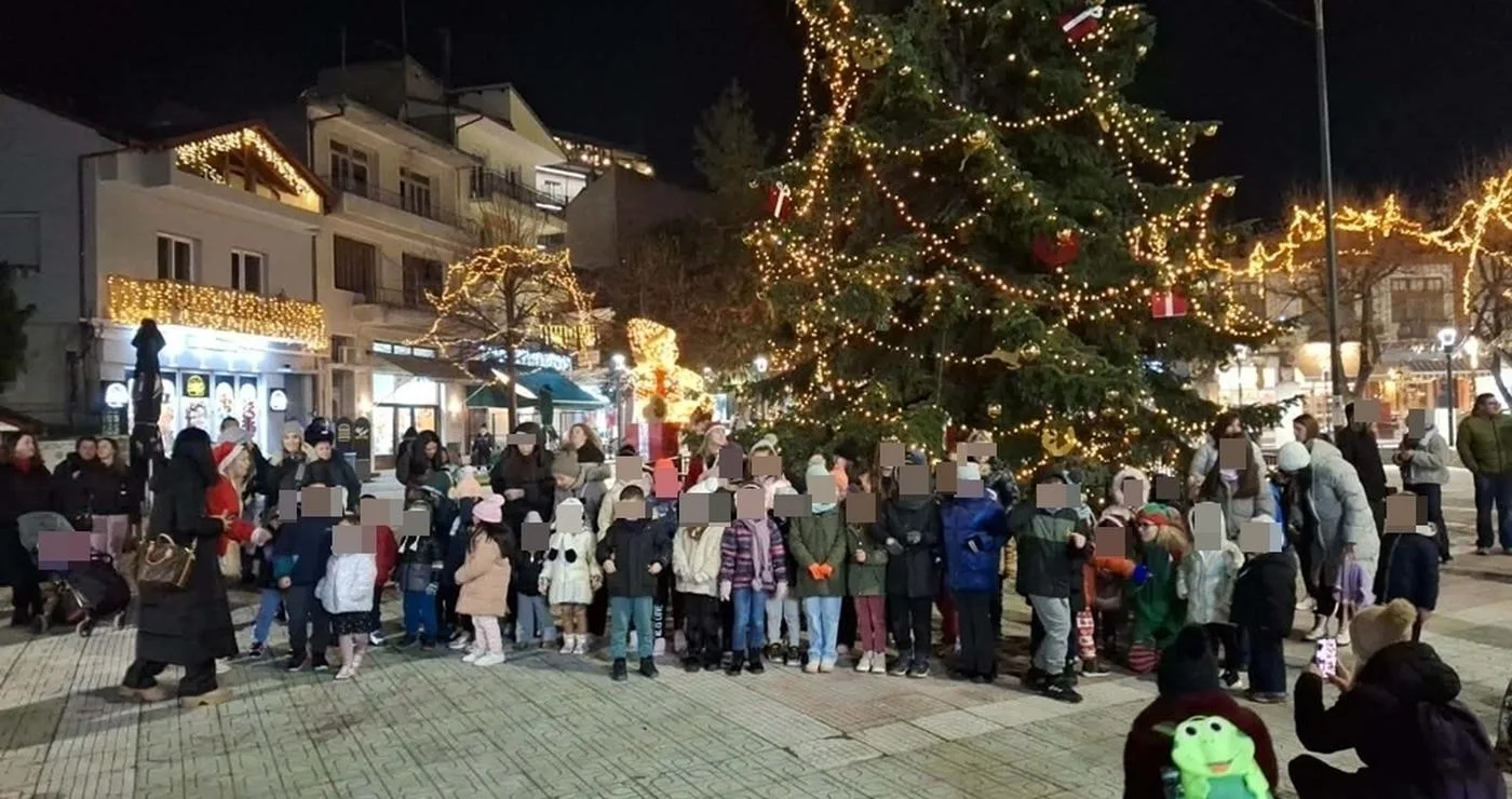 Πλήθος παιδιών και γονέων συγκεντρώνονται γύρω από ένα φωτισμένο χριστουγεννιάτικο δέντρο στην Γιορτή Ζαχαρωτών στη Φλώρινα.