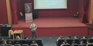 Ο συγγραφέας και Life Coach Χρήστος Τούβε μιλάει στους μαθητές του Γυμνασίου Αμυνταίου για τον σχολικό εκφοβισμό, ενώ μια διαφάνεια προβάλλεται στο φόντο.