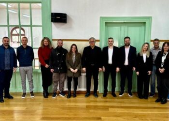 Ομάδα ανθρώπων στέκεται μπροστά από μια σειρά από πράσινες πόρτες στο Τραμπάντζειο Γυμνάσιο στη Σιάτιστα, κατά την εναρκτήρια συνάντηση του έργου Δήμος Βοΐου ReWaste.