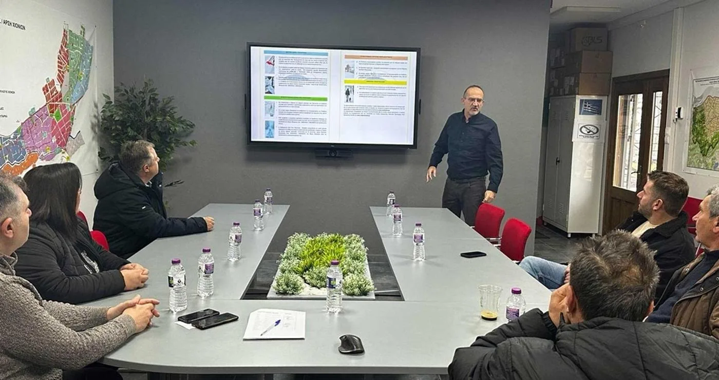 A group of men are seated around a conference table in a meeting room discussing the plan for snow removal in Florina.