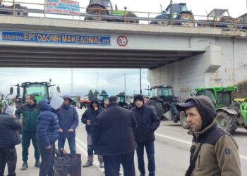 Αγρότες στέκονται κοντά στα τρακτέρ τους στον κόμβο Φιλώτα, ενώ κλείνουν τον δρόμο κατά τη διάρκεια του μπλόκο Φιλώτα.