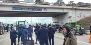 Αγρότες στέκονται κοντά στα τρακτέρ τους στον κόμβο Φιλώτα, ενώ κλείνουν τον δρόμο κατά τη διάρκεια του μπλόκο Φιλώτα.