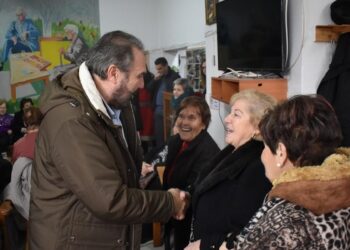 Ο δήμαρχος Φλώρινας ανταλλάσσει χειραψία με μια ηλικιωμένη γυναίκα κατά τη διάρκεια των Χριστουγεννιάτικων επισκέψεων σε ένα ΚΑΠΗ.