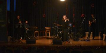 Μια γυναίκα τραγουδάει με μικρόφωνο μπροστά από μια τζαζ μπάντα στην σκηνή, κατά τη διάρκεια των χριστουγεννιάτικων εκδηλώσεων Φλώρινας.