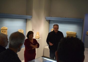 Ένας άνδρας εξηγεί τα αρχαιολογικά ευρήματα σε μια ομάδα επισκεπτών στην έκθεση της Αρχαιολογικής έρευνας Εράτυρας.