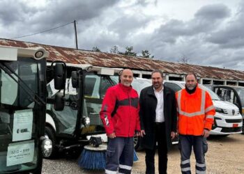 Τρία άτομα στέκονται δίπλα σε ένα ηλεκτροκίνητο όχημα σάρωσης με τον Δήμο Φλώρινας στο φόντο, παρουσιάζοντας τα νέα ηλεκτροκίνητα οχήματα Φλώρινα.