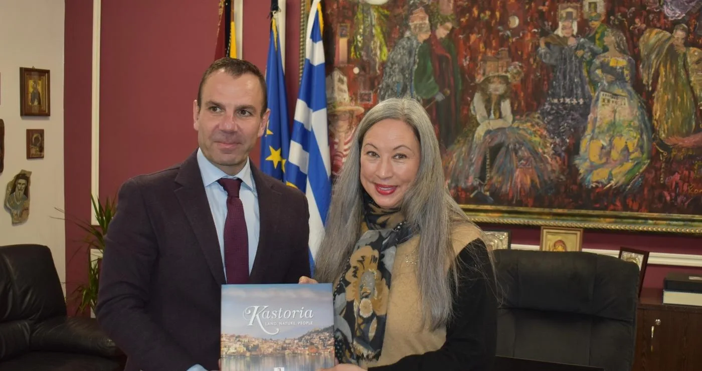 Ο Δήμαρχος Καστοριάς και η Καναδική Πρέσβης χαμογελούν καθώς κρατούν ένα λεύκωμα με θέμα την Καστοριά, υπογραμμίζοντας τη στενή σχέση μεταξύ της πόλης και του Καναδά.