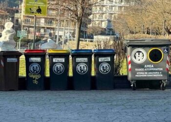 Στην Φλώρινα, μια σειρά από νέους, προσβάσιμους κάδους απορριμμάτων βρίσκονται τοποθετημένοι σε πλακόστρωτο δρόμο, δίπλα σε ένα πάρκο και με φόντο τα βουνά, ενισχύοντας την προσβασιμότητα στην πόλη.