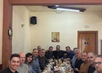 Αστυνομικοί του Αστυνομικού Τμήματος Βεύης Φλώρινας καθισμένοι γύρω από ένα τραπέζι γεμάτο με φαγητά κατά την κοπή πίτας.