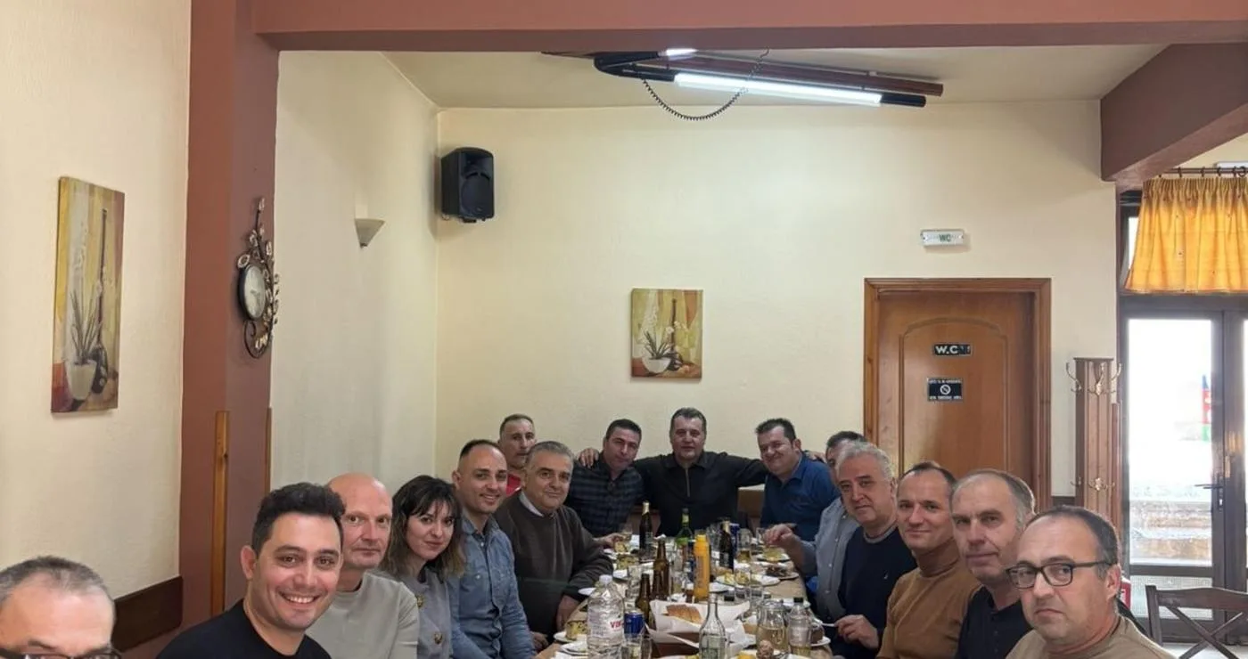 Αστυνομικοί του Αστυνομικού Τμήματος Βεύης Φλώρινας καθισμένοι γύρω από ένα τραπέζι γεμάτο με φαγητά κατά την κοπή πίτας.