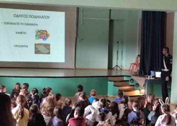 Μαθητές παρακολουθούν ενημερωτική διάλεξη κυκλοφοριακής αγωγής στο Πειραματικό Δημοτικό Σχολείο Φλώρινας, με αστυνομικό να παρουσιάζει τους κανόνες οδικής συμπεριφοράς.