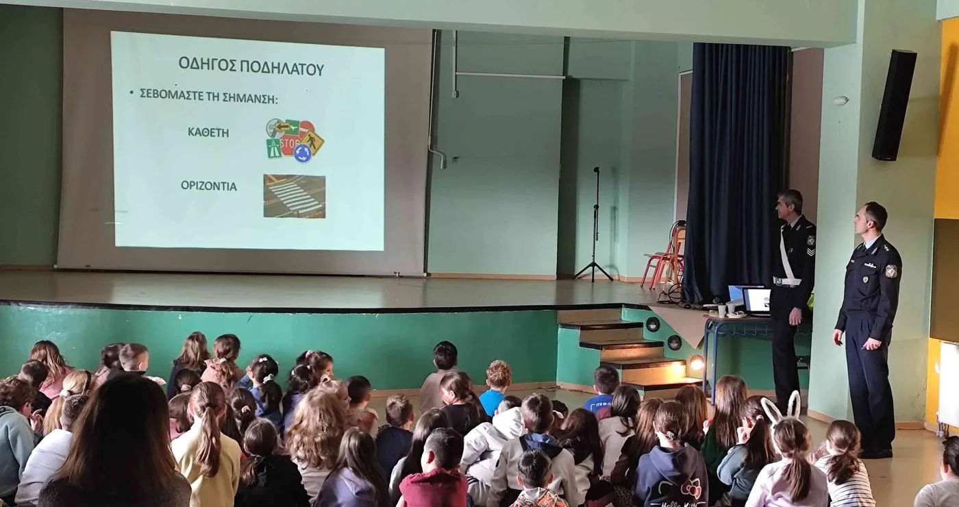 Μαθητές παρακολουθούν ενημερωτική διάλεξη κυκλοφοριακής αγωγής στο Πειραματικό Δημοτικό Σχολείο Φλώρινας, με αστυνομικό να παρουσιάζει τους κανόνες οδικής συμπεριφοράς.