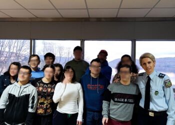 Αστυνομικός στέκεται μπροστά από μια ομάδα ατόμων με αναπηρία στο ΚΔΗΦ «Ευημερία» στην Καστοριά, με θέα τη λίμνη.