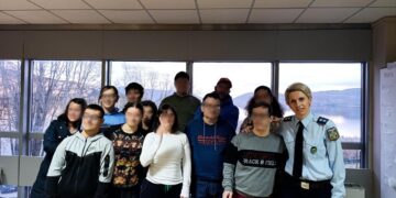 Αστυνομικός στέκεται μπροστά από μια ομάδα ατόμων με αναπηρία στο ΚΔΗΦ «Ευημερία» στην Καστοριά, με θέα τη λίμνη.