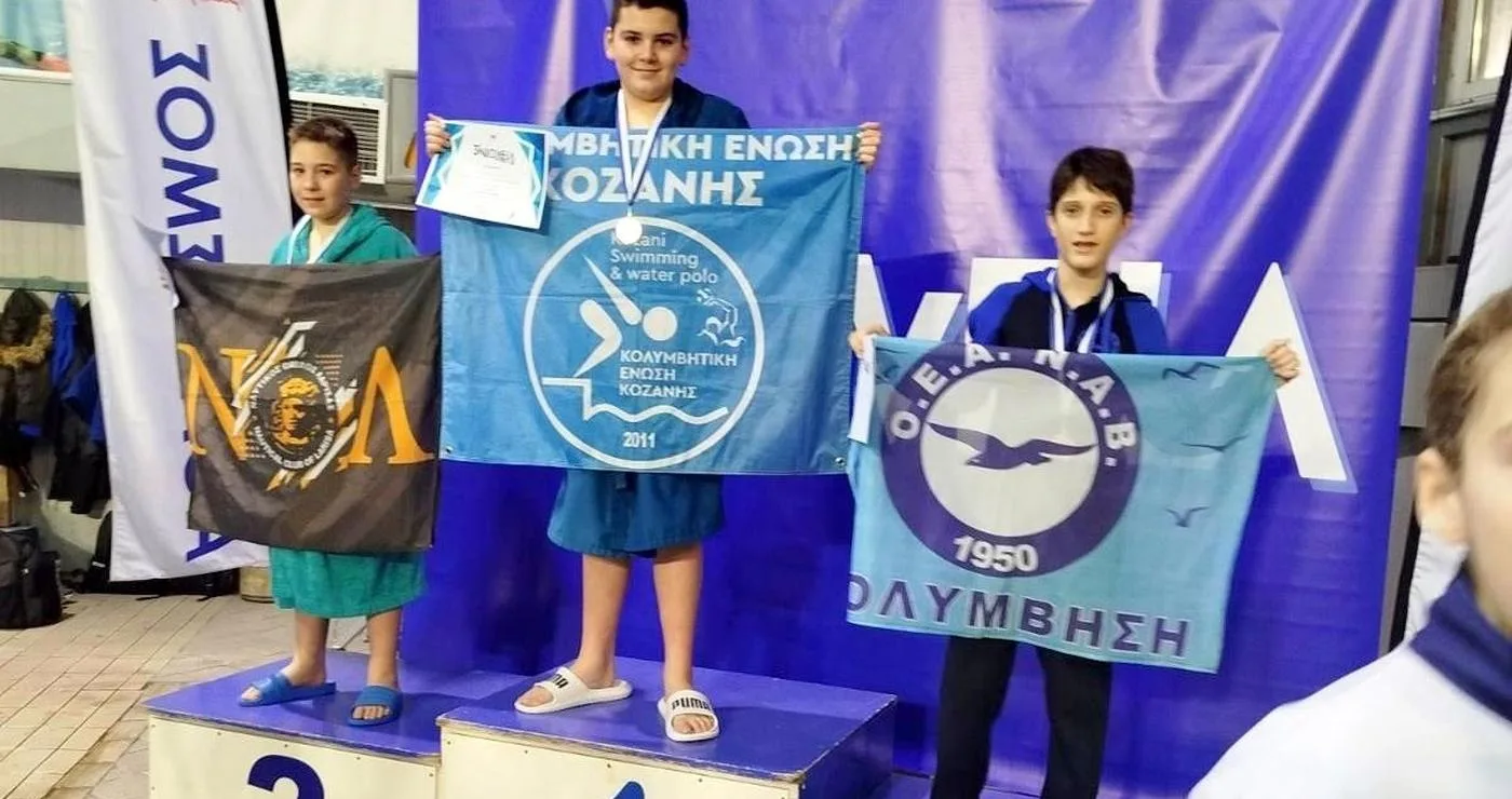 Ένας νεαρός κολυμβητής της Κολυμβητικής Κοζάνης στέκεται στο βάθρο των νικητών με ένα χρυσό μετάλλιο στους αγώνες «Νιόβεια Junior».
