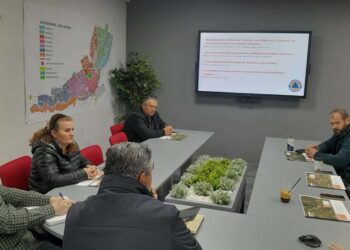 A group of people are seated around a large table in a meeting room discussing αντιπλημμυρικές εργασίες in the municipality of Florina.