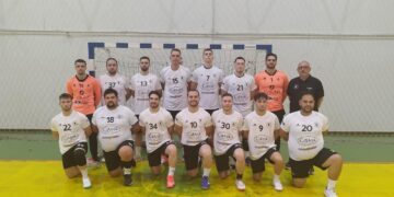 Ομάδα χάντμπολ Αμύντας Αμυνταίου ποζάρει για ομαδική φωτογραφία πριν τον αγώνα, φορώντας κόκκινες φανέλες και μαύρα σορτς. Χάντμπολ αμύντας.