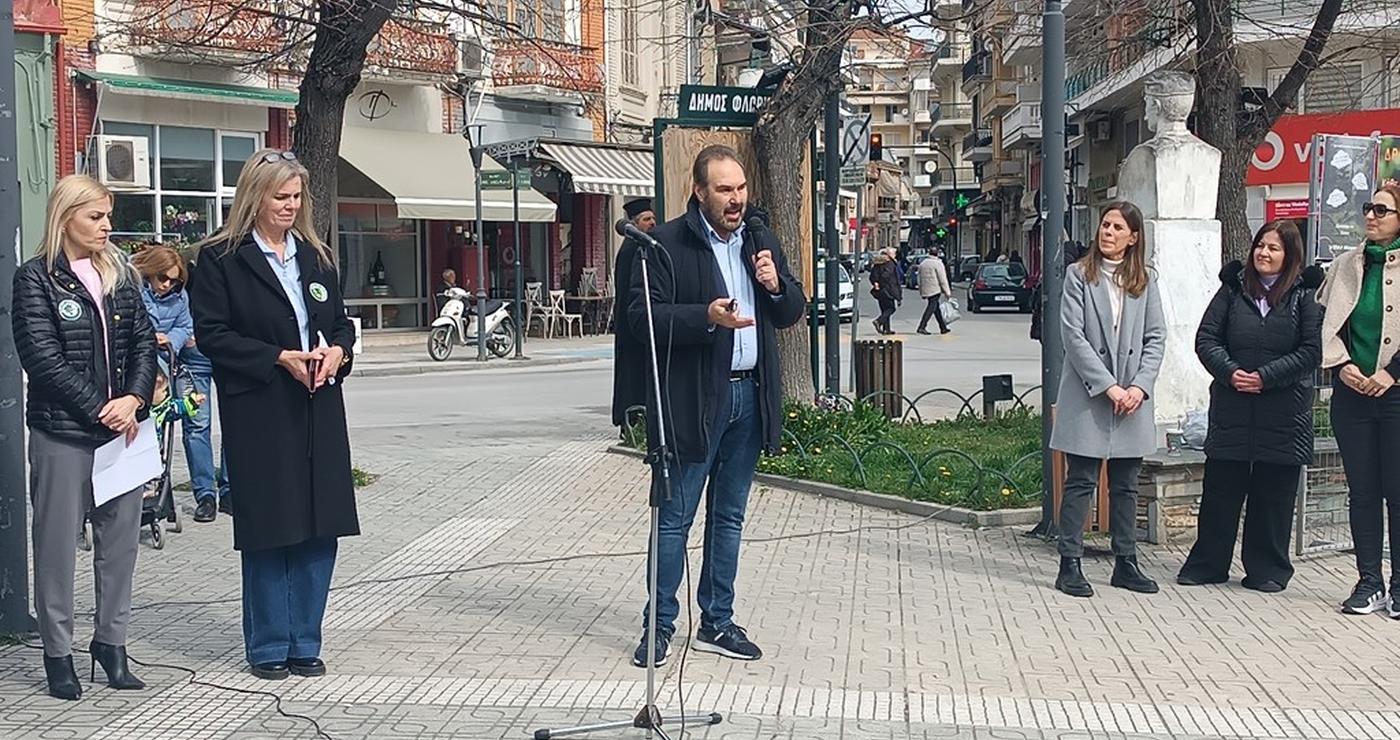 Ένας άνδρας με μικρόφωνο μιλάει στην πλατεία Γ. Μόδη στη Φλώρινα, ενώ γύρω του στέκονται άτομα, στο πλαίσιο της δασικής εκπαίδευσης Φλώρινας.