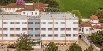 Η πολυώροφη δομή του ΕΠΑΣ Κοζάνης, ο χώρος της εκπαιδευτικής επίσκεψης, φαίνεται σε μια αεροφωτογραφία με γύρω της πράσινη βλάστηση και κτίρια.