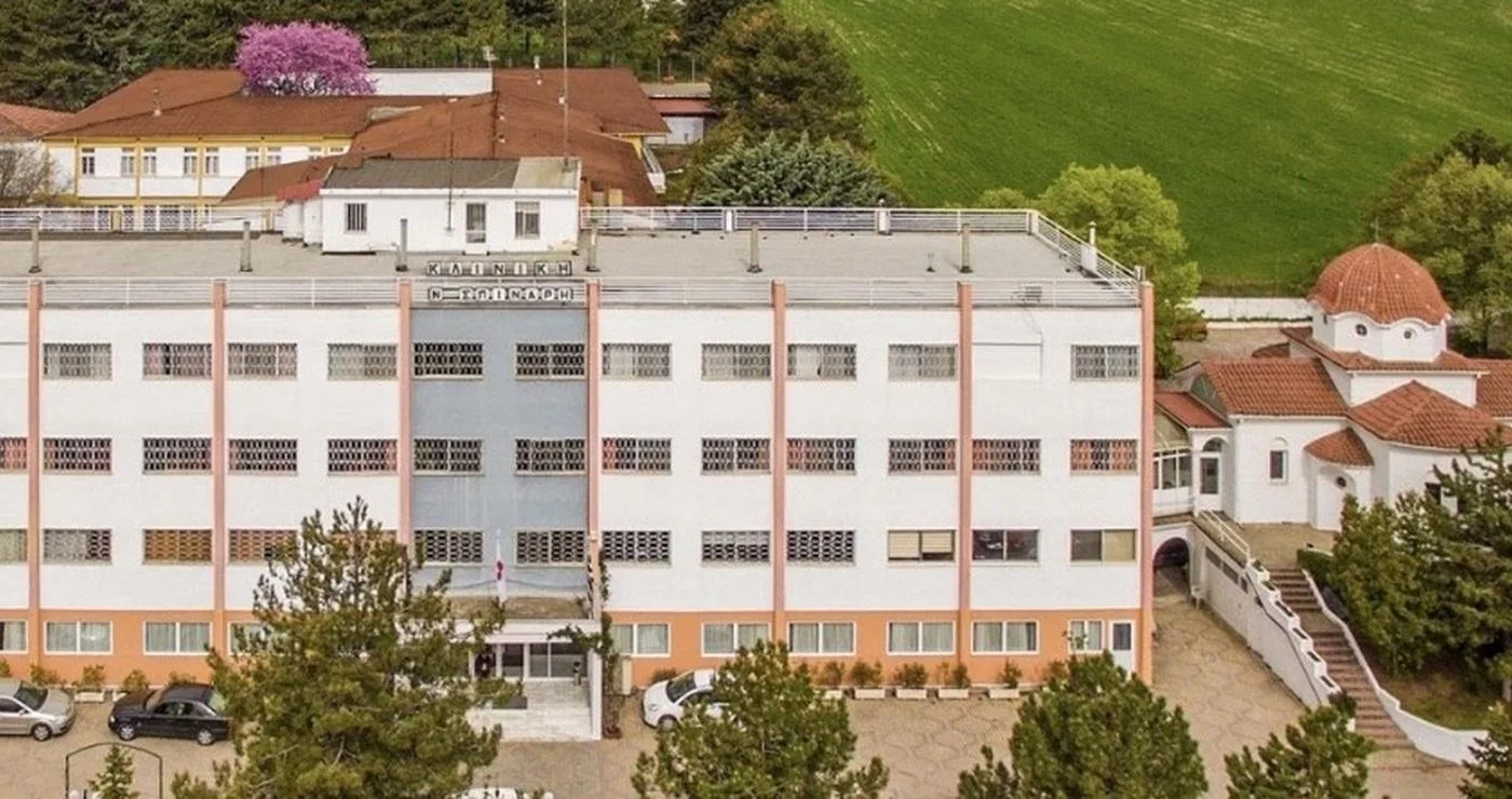 Η πολυώροφη δομή του ΕΠΑΣ Κοζάνης, ο χώρος της εκπαιδευτικής επίσκεψης, φαίνεται σε μια αεροφωτογραφία με γύρω της πράσινη βλάστηση και κτίρια.