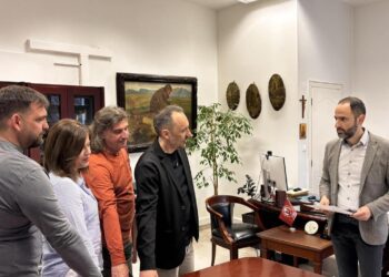 Πέντε νέοι υπάλληλοι του Δήμου Φλώρινας στέκονται γύρω από ένα τραπέζι στο γραφείο του Δημάρχου κατά τη διάρκεια της ορκωμοσίας τους.