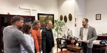 Πέντε νέοι υπάλληλοι του Δήμου Φλώρινας στέκονται γύρω από ένα τραπέζι στο γραφείο του Δημάρχου κατά τη διάρκεια της ορκωμοσίας τους.